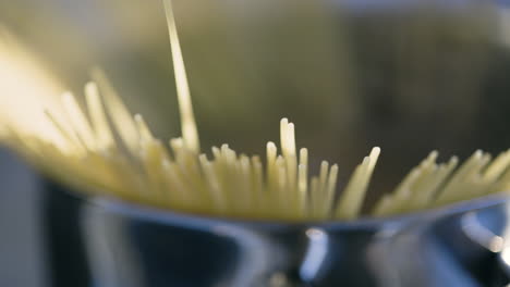 slow close-up pan of spaghetti straws sticking out of steamy pot