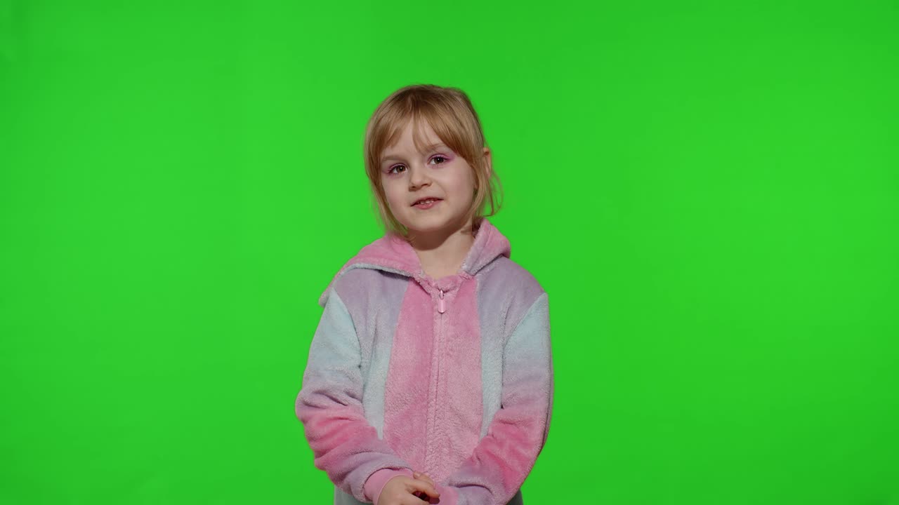 niña en pijama disfrazada de unicornio grabando un mensaje de video hablando por webcam, haciendo una llamada en línea
