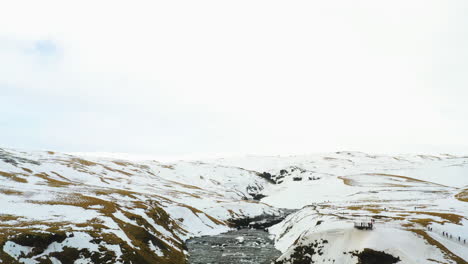 Aerial-tilt-reveal-of-the-Skogafoss-waterfall,-cloudy-winter-day-in-Iceland