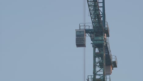 a close-up of a high-rise building under construction, with visible concrete structures and scaffolding, beside a crane, captured at dusk