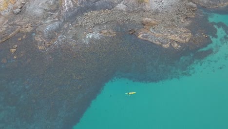 Aerial-view-of-a-tandem-kayak-exploring-a-remote-and-rugged-rock-island-in-the-pacific-ocean