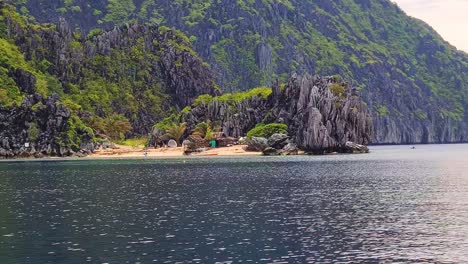 Playa-Tropical-Escondida-Y-Cabaña-De-Madera-Bajo-Rocas-De-Piedra-Caliza,-El-Nido,-Palawan,-Filipinas