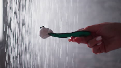 woman cleans razor in water sprays in bathroom closeup. lady washes blade under falling down drops in shower unit. cleaning shaver after usage