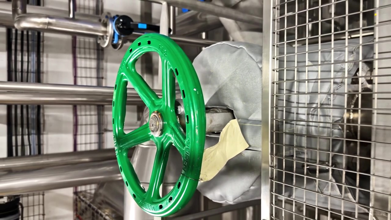 Large green industrial flywheel rotating as part of mechanical system in factory setting