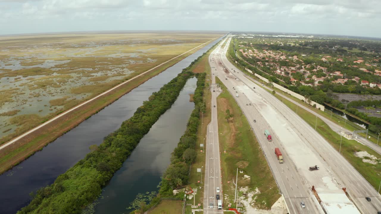 Drone shot of the Sawgrass Expressway and the Florida Everglades, next to the Levee. Moving Forward, with Sawgrass Expressway and Neighborhoods on the Right.