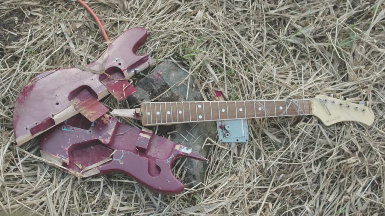 guitarra eléctrica roja rota en el suelo