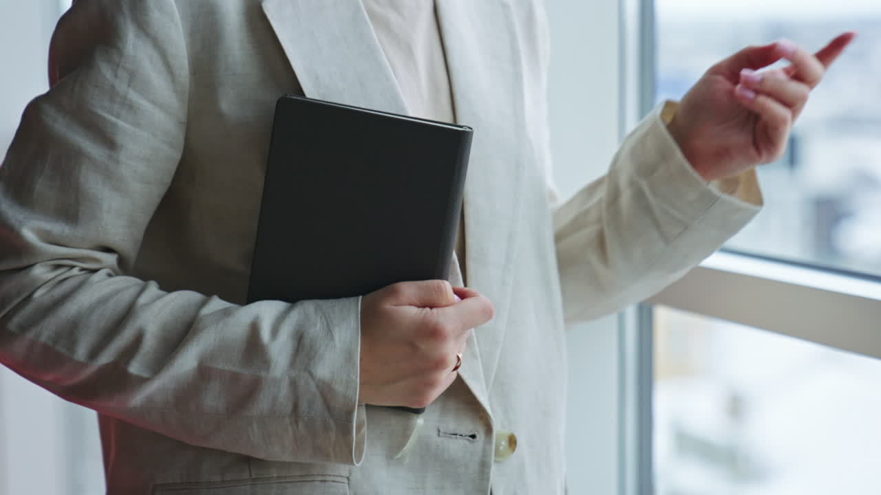 Female hands holding a paper notebook in black cover. Unrecognizable woman opens the book. Close up.
