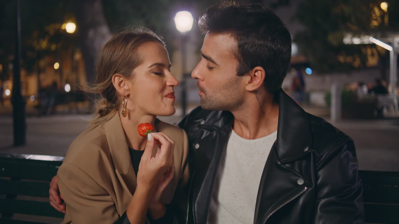 Date couple tasting strawberry on evening street closeup. Happy people in love