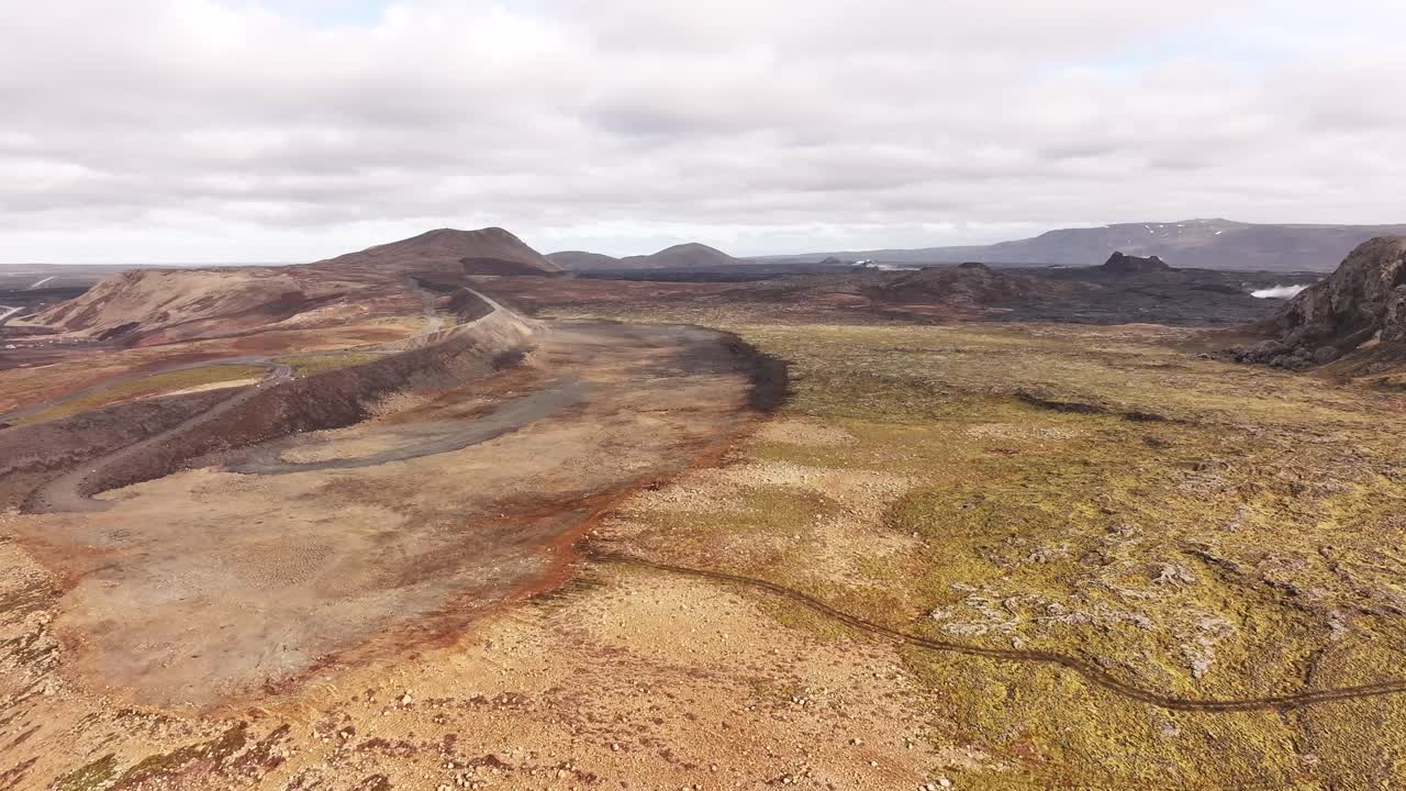 Drone moving forward over a rugged volcanic landscape in Iceland under cloudy skies