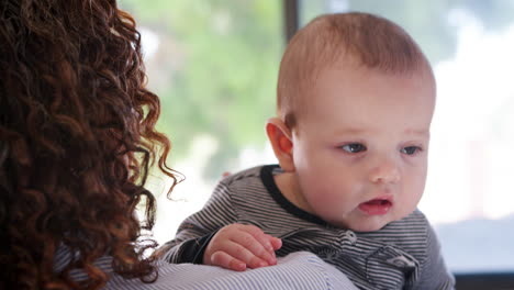 baby grandson looking over grandmothers shoulder as she cuddles him