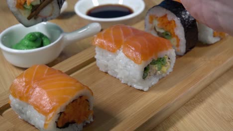 Kaukasische-Hand-Nimmt-Sushi-Mit-Stäbchen-Auf-Und-Taucht-Es-In-Wasabi-Sauce