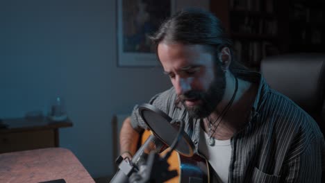 man singing and playing acoustic guitar in home studio
