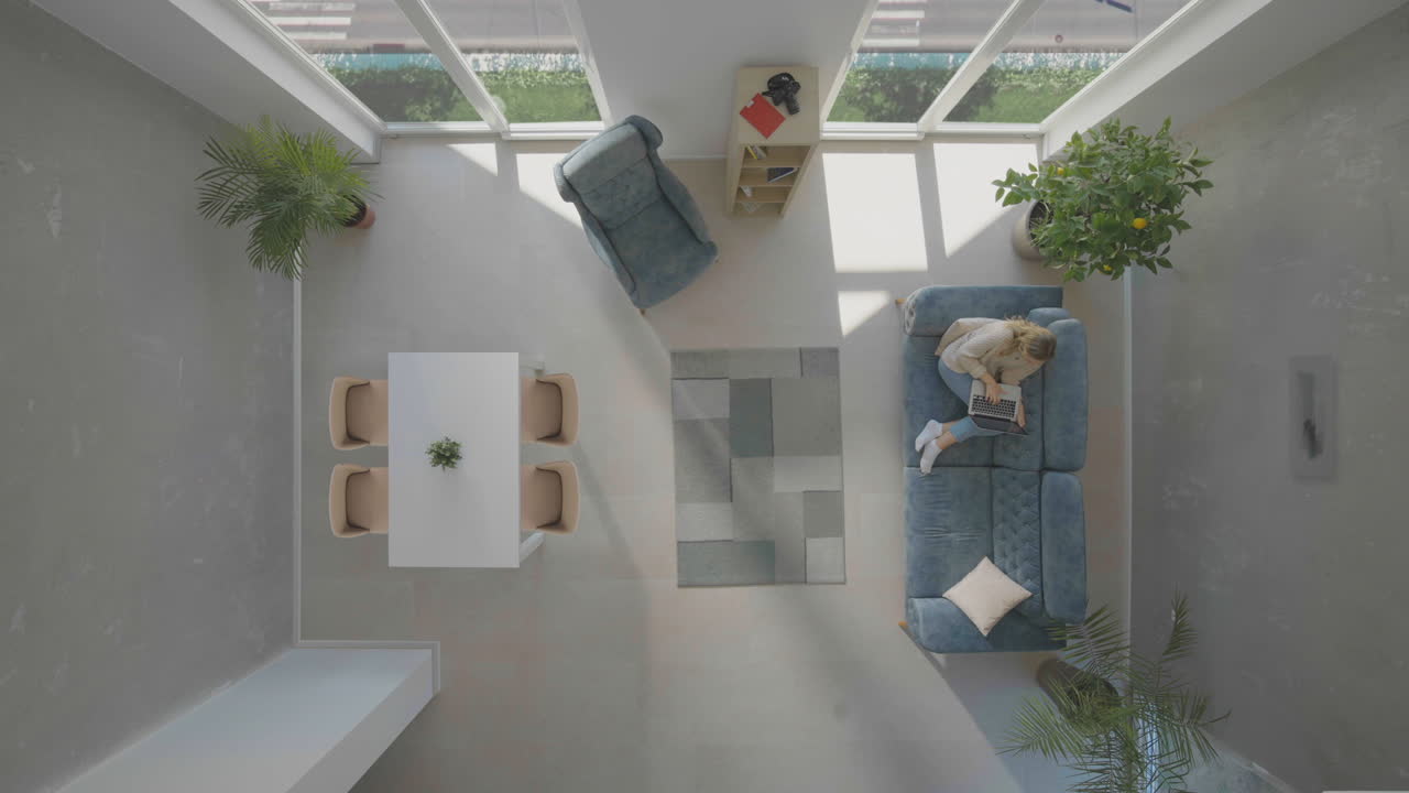 una mujer sola sentada en el sofá con una computadora portátil