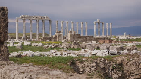 una fila de antiguas columnas en un campo con piedras esparcidas en laodicea