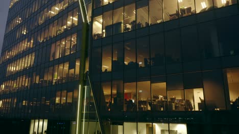 drone shot up at the windows of a night skyscraper. opening hours in the office building at night.