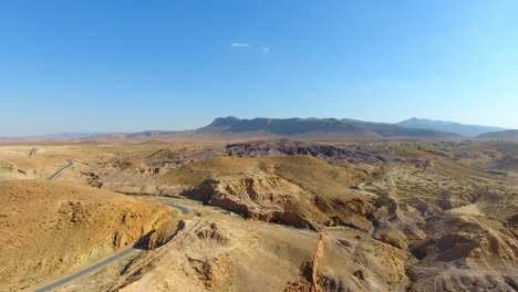 Drohnenaufnahme-Einer-Straße-Mit-Autos-Zwischen-Wüstenbergen-In-Bousaada,-Algerien