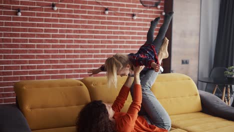 mother lifting girl in air on her ankles, pretending to fly