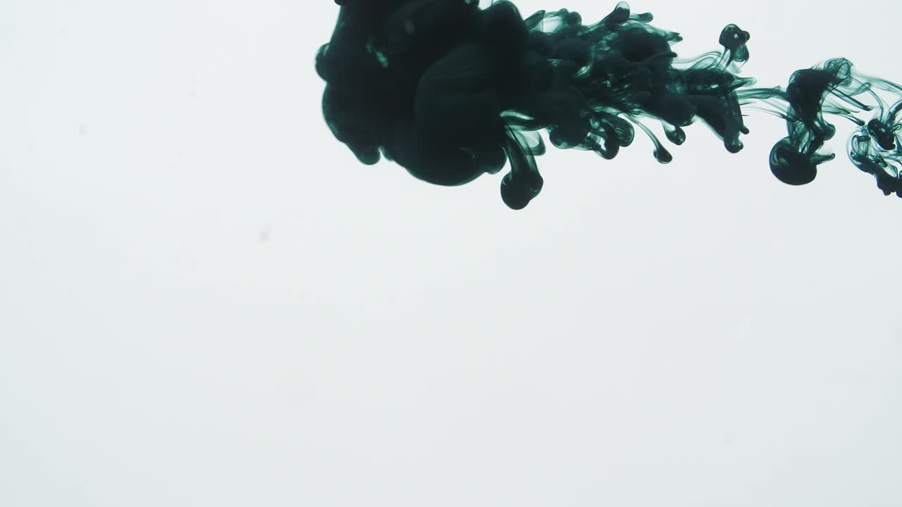 Green Ink Sprayed Into Water On A White Background