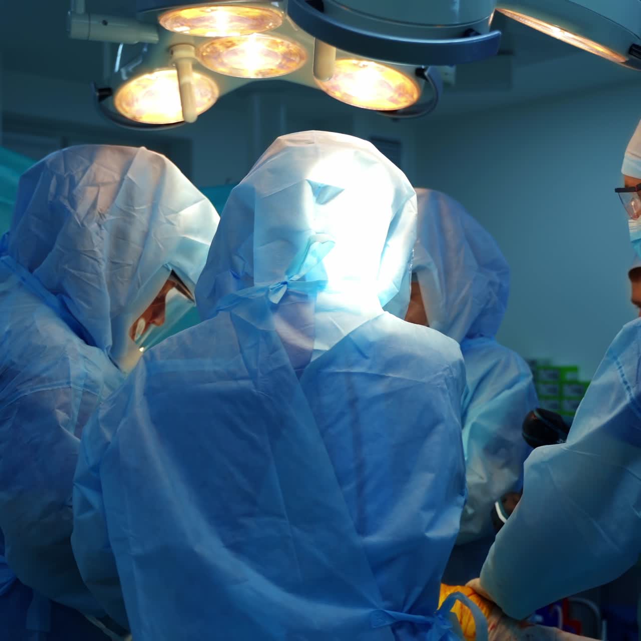 Group of doctors in safety suits. Surgical procedure by team of specialists in medical uniform in operating room. The ending of pandemic.