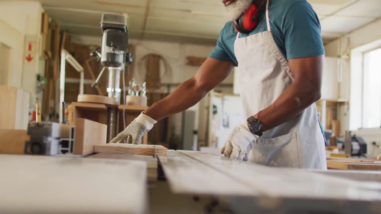 Close up of african american male carpenter hand's using table saw for cutting wood