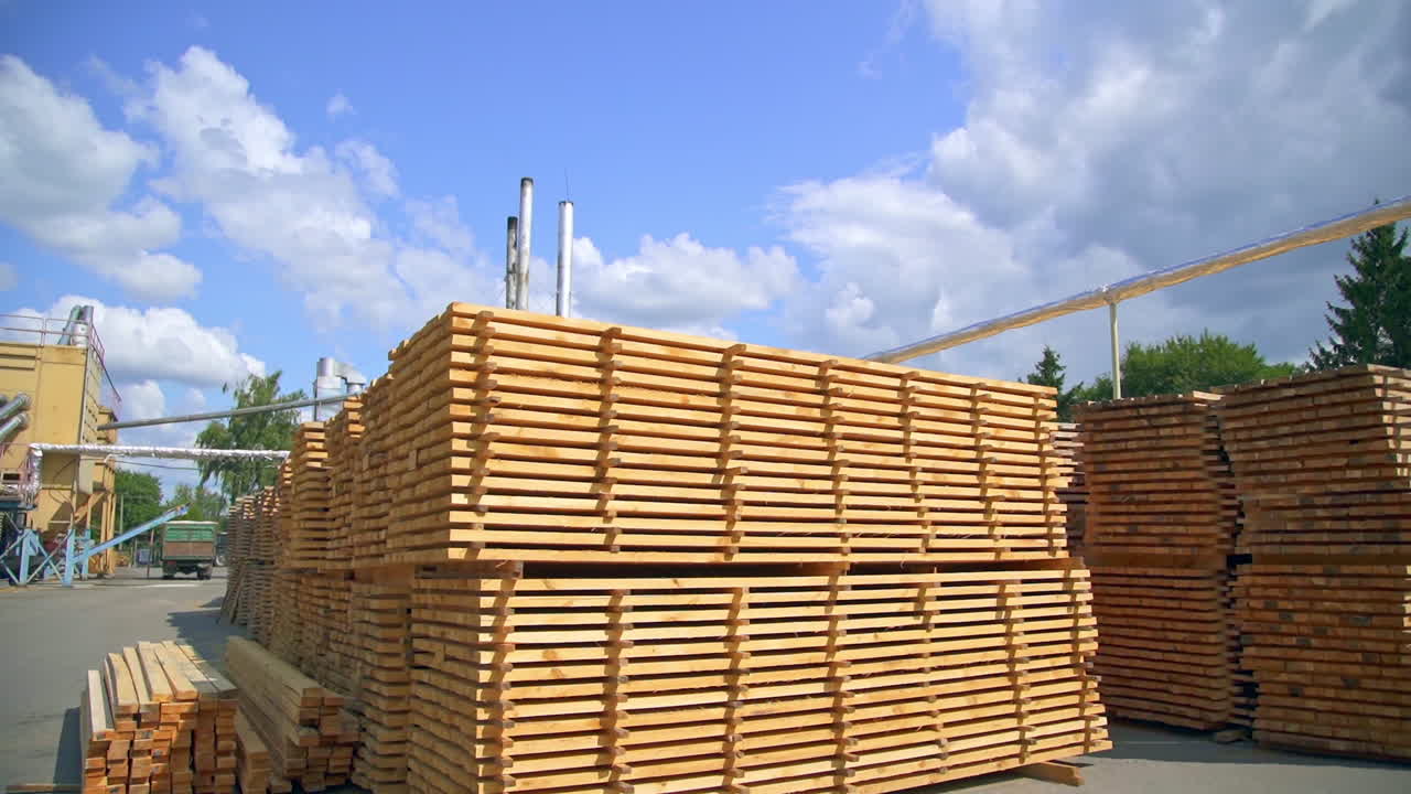Territory of modern plant with stored materials outside. Piles of wooden balks for producing doors.