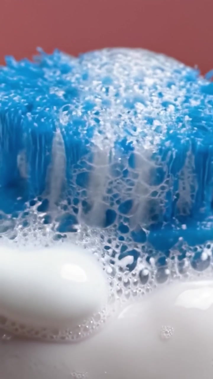 Primo Piano di uno Spazzolino Blu che Spazzola la Schiuma su una Superficie Bianca, Catturando l'Azione del Dentifricio e delle Bolle in un Ambiente Vibrante e Pulito