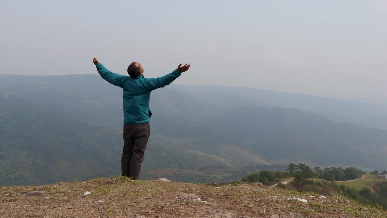 hombre disfrutando de la naturaleza en la cima de la colina con el fondo de la furia de la montaña brumosa desde un video de ángulo plano tomado en nongjrong meghalaya india