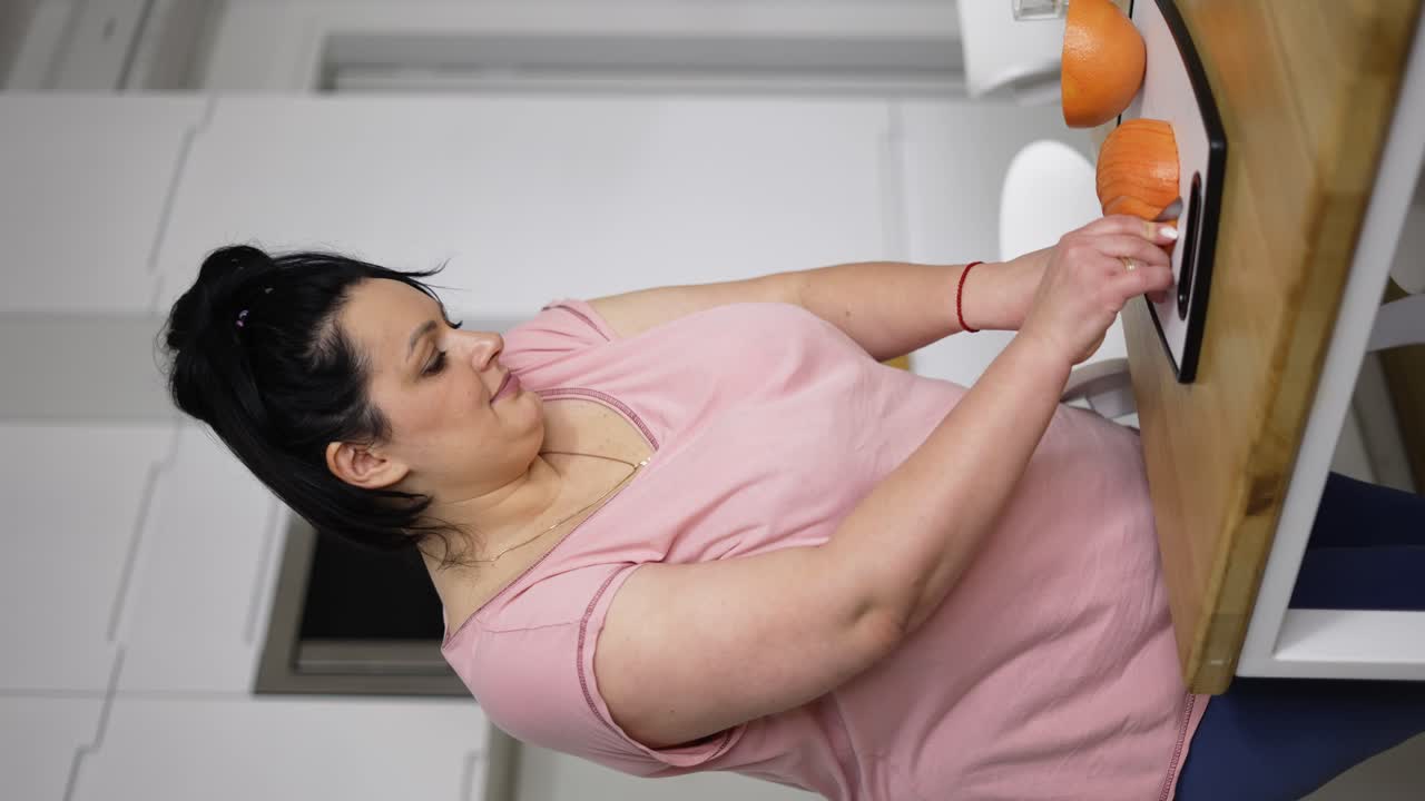 Attraente donna in sovrappeso che prepara un pasto sano, tagliando un pompelmo, primo piano