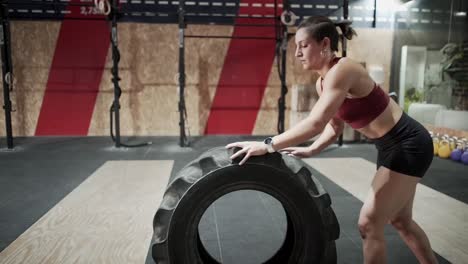 woman performing tire flip exercise in gym