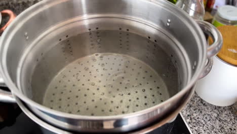 agua caliente hirviendo y matando gérmenes en una sartén sobre una cocina eléctrica en la cocina