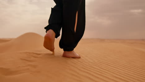 primer plano de pies descalzos caminando por las dunas de arena en el desierto del sáhara