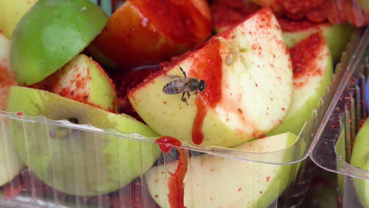 una pequeña abeja alimentándose de chamoy derramado sobre manzanas