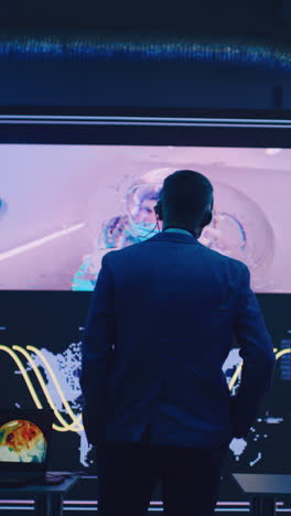 anonymous flight director in suit walking towards big screen with astronaut during remote spacecraft launch in control center. vertical shot.