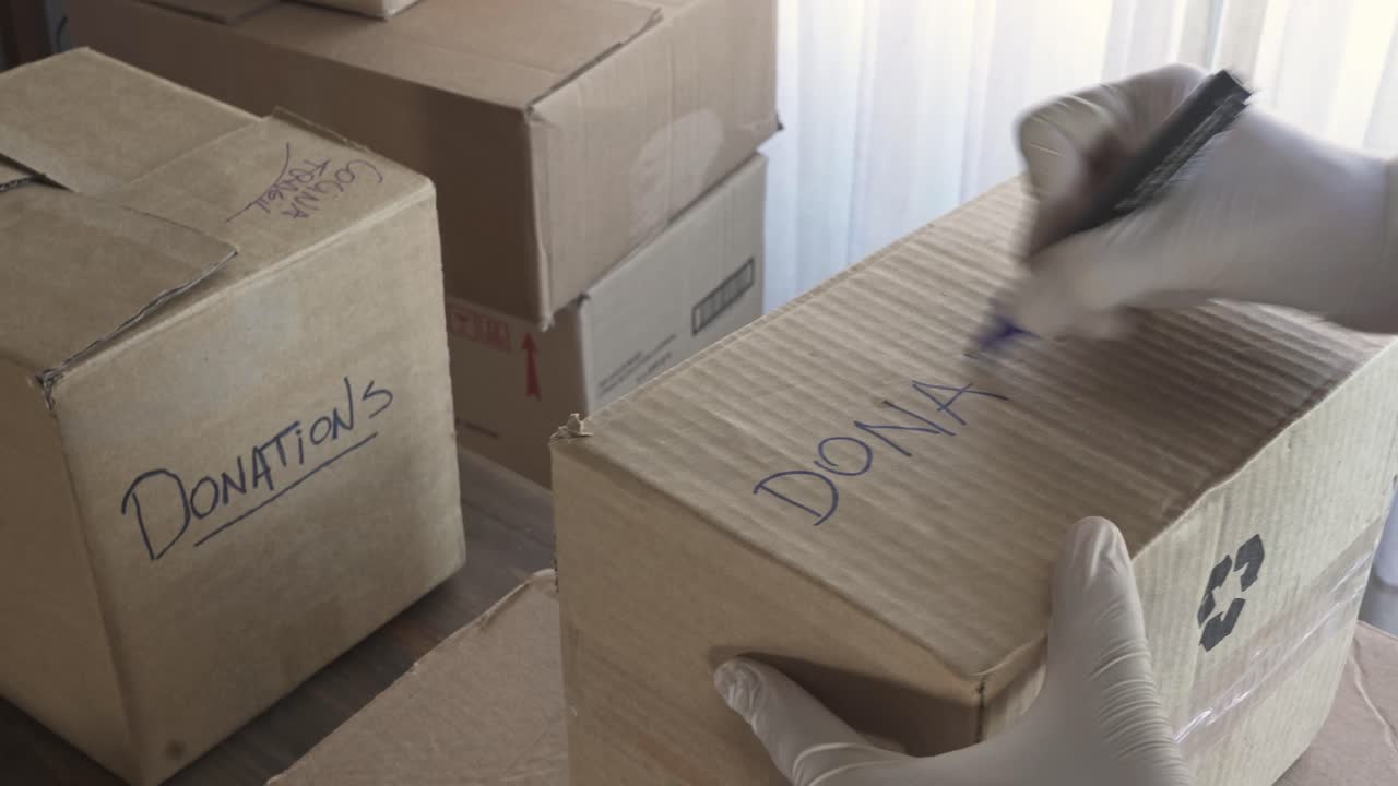Person Taping and Labeling Cardboard Box for Donations