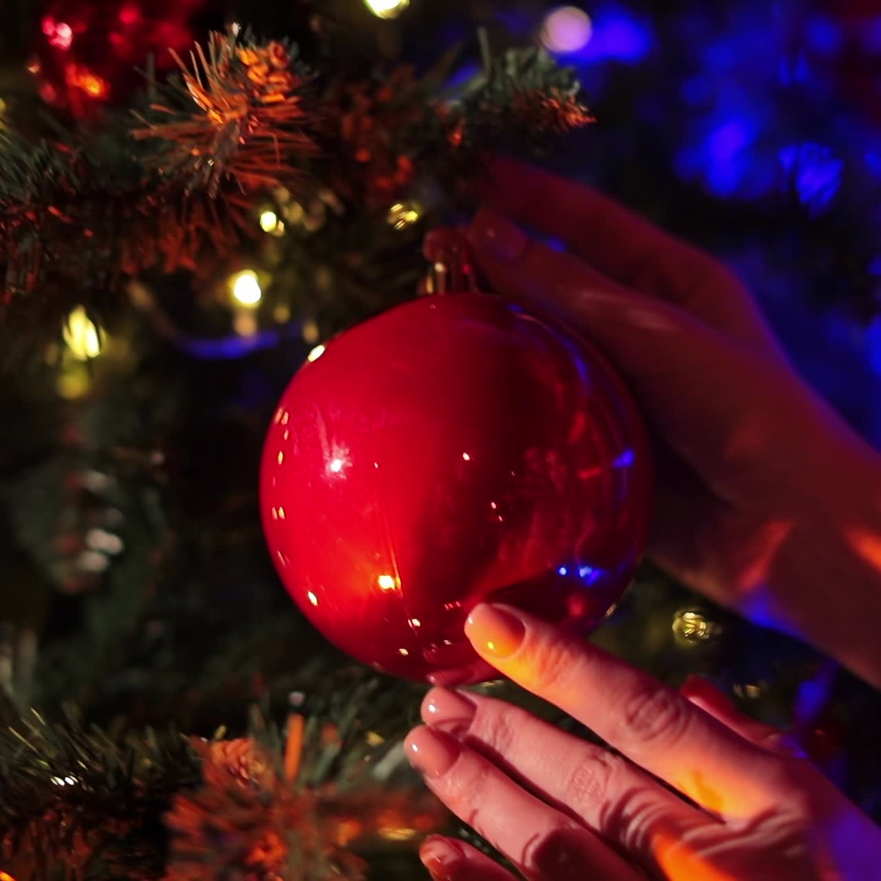 Girl's hands decorating Christmas tree for celebrations. Male hand covers gently the female hand. Blurred backdrop