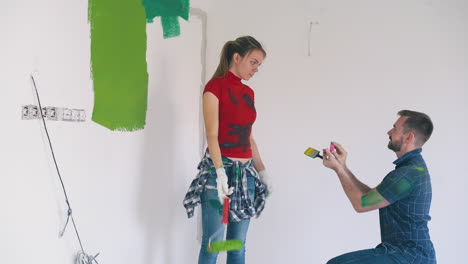 el hombre le propone a la hermosa chica pintar la pared en la habitación