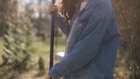 Close-up-view-of-caucasian-woman-removing-weeds-with-a-rake-in-the-countryside.-Then-she-looks-at-camera