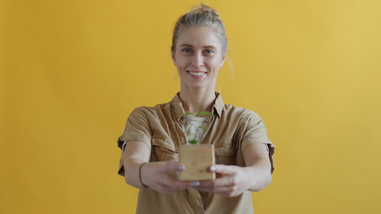 Woman Holding a Small Plant in a Wooden Pot