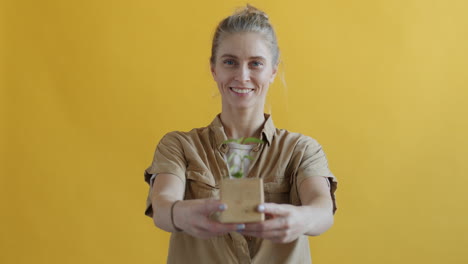 woman holding a small plant in a wooden pot