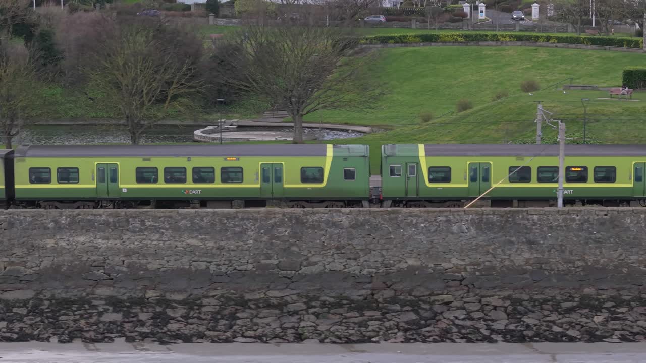 Train passing through Blackrock district in Dublin with park and water in background