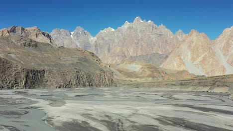 slow moving aerial drone panning up from the river and revealing passu cones mountains in hunza pakistan next to the famous hussaini bridge