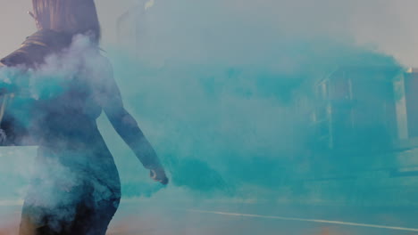 Chica-Bailando-Con-Granada-De-Humo-Azul-En-La-Ciudad-Joven-Mujer-Rebelde-Celebrando-La-Expresión-Creativa-Con-Baile-En-Cámara-Lenta-De-La-Calle