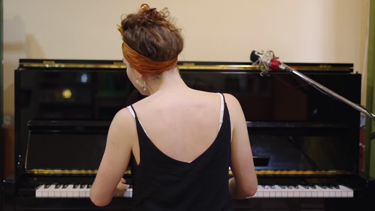 A musician playing the piano, viewed from behind