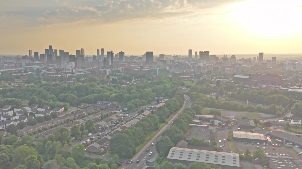 Manchesterin siluetti Beswickistä, lähellä Etihad Campus -aluetta, Itä-Manchesterissa, Englannissa, Yhdistyneessä kuningaskunnassa, asuinalueiden, puiden latvustojen ja liikenneväylien yläpuolella, dronen liukukuvaus.