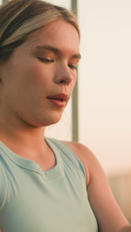 joven sentada cerca de la barandilla de hierro limpiando la suciedad de la palma, respirando profundamente mientras mira a la distancia con expresión pacífica, la luz del sol de la tarde iluminando su rostro