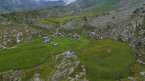 aerial overhead view resort village lodge buildings in valmalenco, surrounded by wide pastures and a pretty mountain pasture, alpe prabello