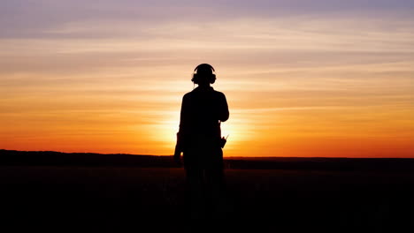 silhouette of a person wearing headphones against a sunset
