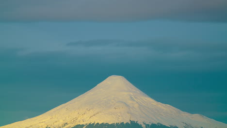 Lapso-De-Tiempo-De-La-Puesta-De-Sol-Sobre-El-Volcán-Osorno-Con-Nieve-Cubriendo-Las-Colinas,-Puesta-De-Sol-Dorada