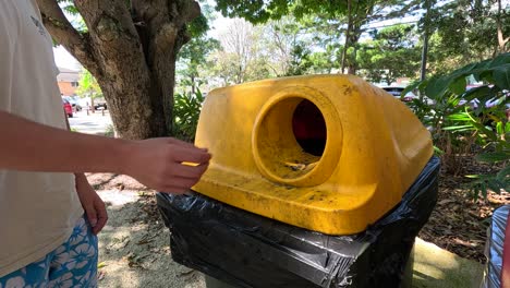 person disposing of a can in a bin