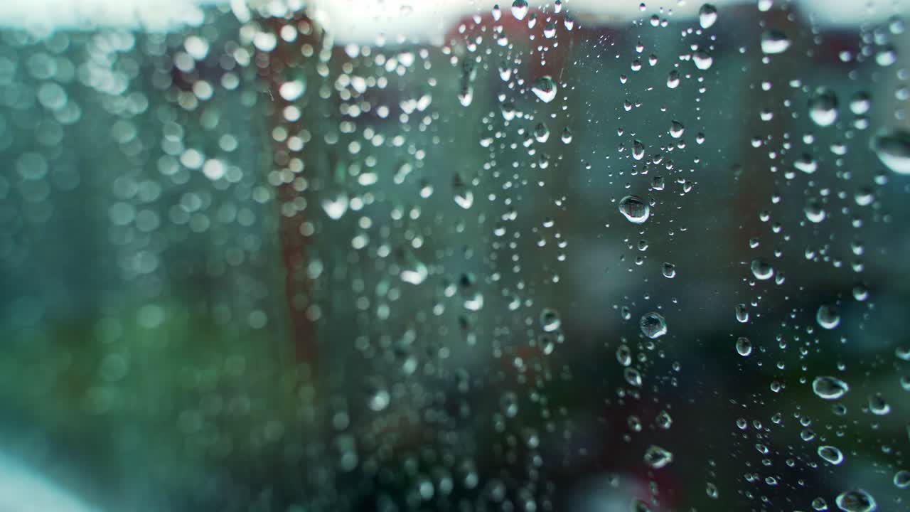 Bad weather. Rain falling outside. Rain on the glass. Rain drops on glass window. Water drops moving down on glass.